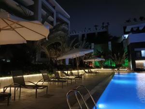 开罗Sheraton Ocean 803 - Private apartments的一座带椅子和遮阳伞的游泳池位于一座建筑旁边