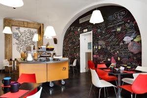 那不勒斯Hotel Piazza Bellini & Apartments的一间设有红色椅子的餐厅,墙上有涂鸦