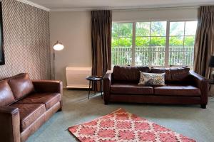 罗托鲁瓦Silver Fern Rotorua Suites & Spa的客厅配有两张真皮沙发和地毯。