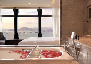 香港One-Eight-One酒店及服务式住宅的带浴缸的浴室、一张床和窗户