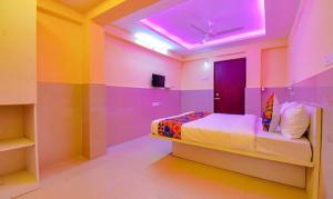 浦那FabHotel Empire Executive的卧室设有粉红色和紫色的墙壁和一张床