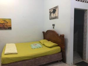 不拉士打宜Friendjoss Homestay Laugumba RedPartner的一间卧室配有一张黄色床单和墙上的照片。