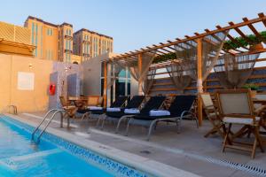 多哈Ivory Inn Hotel Doha Qatar的一组椅子坐在游泳池旁