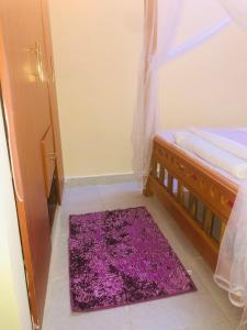 蒙巴萨Mtwapa Apartment的卧室,床边有紫色地毯
