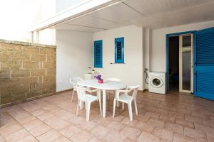 托雷莫泽Appartamento climatizzato a 50 m dalla spiaggia con patio esterno的庭院配有白色桌椅和洗衣机。
