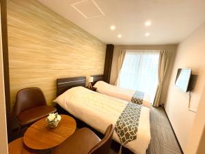 东京Sugamo Winco Residence的酒店客房带两张床和一张桌子以及椅子。