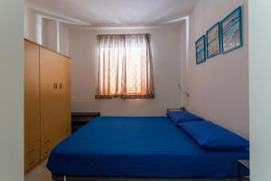 丽都玛里尼Bilocale climatizzato a 50 m dalla spiaggia con posto auto privato的一间卧室设有蓝色的床和窗户。