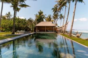 甘地达萨Villa Manis Beachfront Candidasa的一个带凉亭和棕榈树的游泳池