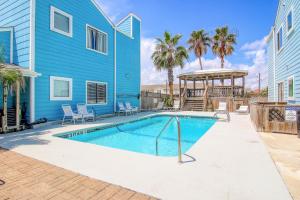 帕德雷岛Lyla's Beach Getaway的蓝色房子前的游泳池