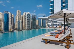 迪拜迪拜码头及游艇俱乐部葳达酒店的大楼内一个带椅子和遮阳伞的游泳池