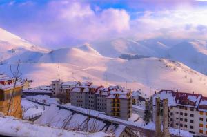 普拉托讷沃斯Zona Piazzale del Prel的雪中城市,以山为背景