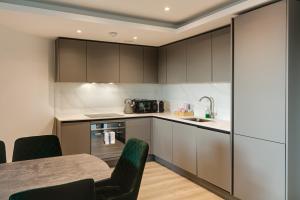 布伦特福德Brentford Apartments by Charles Hope的厨房配有灰色橱柜和桌椅