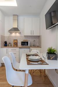 格拉纳达Granaxperience Apartamentos La Maleta的白色的厨房配有白色的桌子和椅子