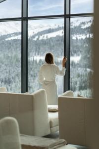 克尼格利斯滕URSPRUNG Panorama Hotel Königsleiten的白雪 ⁇ 的山中,从窗户望出去的女人