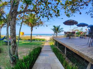 瓜拉图巴Spazio Marine Hotel - Guaratuba的通往海滩的木板路,配有桌子和遮阳伞