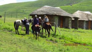 MokhotlongLibibing chalets的一群人骑马在小屋前