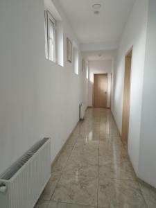 巴统MARSEİLLE PALACE HOTEL的一条空的走廊,有白色的墙壁和瓷砖地板