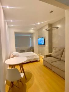 里约热内卢Apartamento Encantador Leme - Prédio na Orla的一间卧室配有一张床、一张桌子和一张沙发