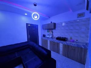 拉各斯DINERO JADE - One Bedroom Apartment的一间配有沙发的客房和一个带蓝色灯光的厨房
