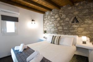米克诺斯城Mykonos Amazing Apartments 2的一间卧室设有一张床和石墙