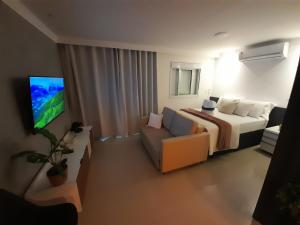 瓜鲁柳斯Studio 1202 Guarulhos Aeroporto的一间卧室配有一张床、一张沙发和一台电视。