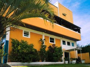 瓜鲁雅伯南布哥太阳酒店的一座黄色的建筑,前面有棕榈树