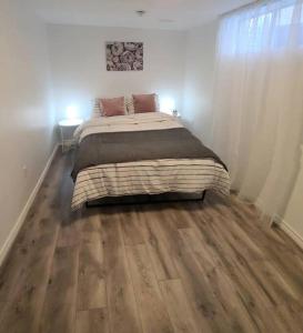 巴里Cozy 2-bedroom lower unit!的一间卧室设有一张大床,铺有木地板