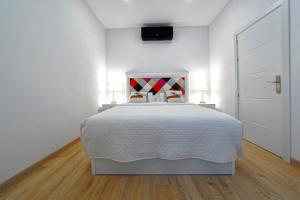 因赫尼奥CASA VERDE Comfortable Air-Conditioned Modern Apartments的一间白色卧室,配有一张床和两盏灯