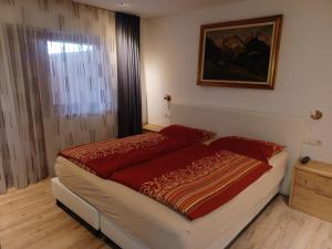 多比亚科kuglerhof的一间卧室配有一张带红色棉被的床和窗户。