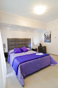罗马多莫斯芬提斯酒店的一间卧室配有一张带紫色床单的大床