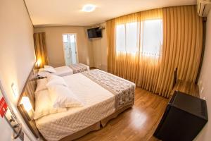 坎普拉古Hotel Campo Largo Comfort的酒店客房设有两张床和电视。