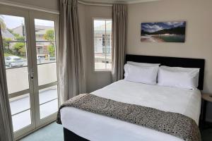 罗托鲁瓦Silver Fern Rotorua Suites & Spa的一间卧室设有一张床和一个大窗户