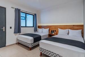 梅里达Hotel Mody Merida的酒店客房设有两张床和窗户。