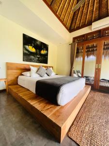 金巴兰La Reserva Villas Bali的卧室配有一张床铺,墙上挂着黑猫画