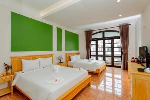 会安Sea and Sand Hotel的一间卧室设有两张床和绿色的墙壁
