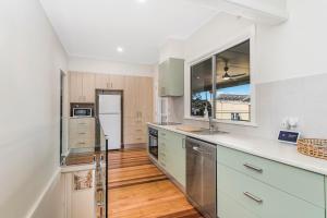 麦夸里港Lazy Stays的厨房配有白色橱柜和木地板。