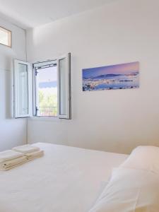 特劳洛斯Villa Elpiniki的一间白色卧室,配有床和2个窗户