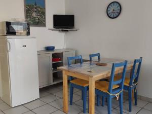 奥雷龙圣乔治Appartement Saint-Georges-d'Oléron, 2 pièces, 4 personnes - FR-1-246A-117的厨房配有木桌、椅子和冰箱