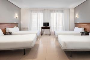 瓦尔德莫罗Hotel Victoria Valdemoro的酒店客房设有白色的床和电视。