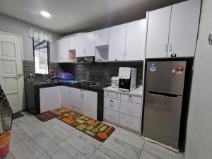 仙本那ANG LEE HOLIDAY HOME 1的厨房配有白色橱柜和不锈钢冰箱