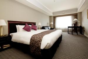 仓敷仓敷皇家艺术酒店的酒店客房配有一张带紫色枕头的大床