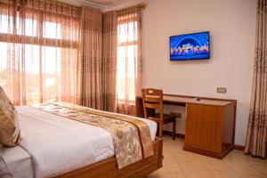 纳库鲁Grand Winston Hotel的一间卧室配有一张床和一张书桌及电视