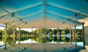 杰尔Gyirmót Sport & Wellness Hotel的一个带蓝色椅子和湖泊的帐篷