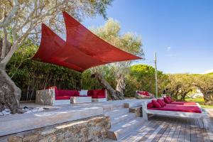圣特罗佩Vyylla Private Resort的一个带红色家具和红色遮阳伞的庭院