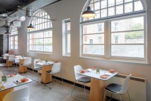 爱丁堡KM Hotel的餐厅设有白色的桌椅和窗户。