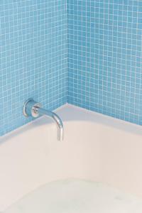 布雷斯肯斯米利阿诺酒店的带浴缸的浴室和蓝色瓷砖墙