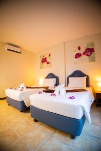 芭东海滩Rico's Patong Hotel的两张位于酒店客房的床,上面有鲜花