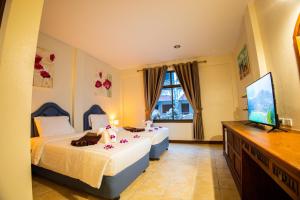 芭东海滩Rico's Patong Hotel的一间卧室配有两张床和一台平面电视