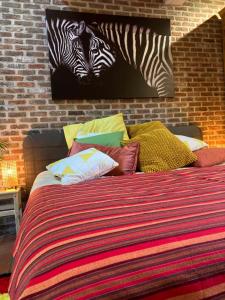 KeerbergenKaribu Keerbergen的一张带色彩缤纷的枕头和墙上斑马的床