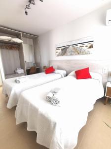 TózarMagical Andalusian Vacation "Los Arcos"的配有白色床单和红色枕头的客房内的两张床